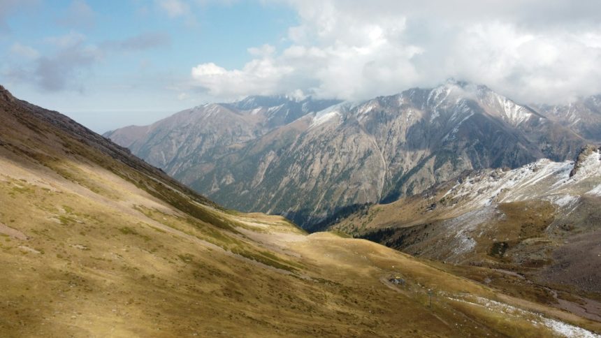 قمم جبلية مغطاة بالثلج والغيوم من أعلى منتجع شيمبولاك قرب ألماتي